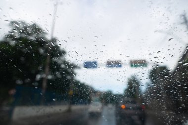 Bulanık görüş, trafik akışı sırasında caddede bir arabanın camına damlayan yağmur damlaları. Doku. Arkaplan