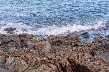 Alçak gelgit sırasında kumsal dalgalarının karanlık kayalara çarpması görüntüsü. Cennet kumsalı. Kusursuz bir mizaç. Brezilya.