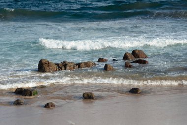 Güzel bir plajın deniz kıyısındaki karanlık kayalar. Dalgalar kumların üzerinde kırılıyor, cennet. Brezilya