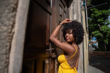 Sarı elbiseli güzel bir kadının portresi eski kahverengi ahşap kapının yanında duruyordu. Mutlu insan seyahat konsepti.