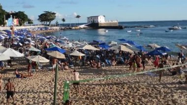 Gün batımında denizde yıkanan turistlerle dolu Porto da Barra plajı manzarası. Salvador, Bahia.