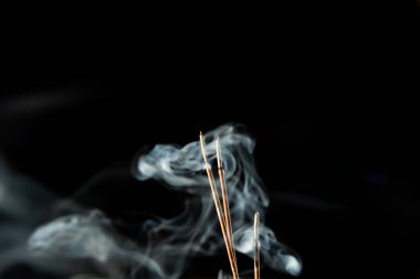 Siyah arka planda duman olan üç yanan tütsü çubuğu. Stüdyo çekimi.