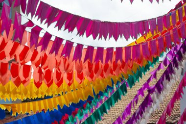 Koloni evlerinin arka planına karşı renkli dekoratif flamalar. Plastik parti eşyaları. Brezilya.