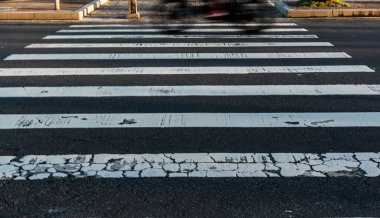 Hızla geçen bir araçla yıpranmış bir yaya geçidi. Hareket, bulanıklık. Trafik levhası. Brezilya.