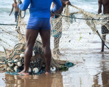 Kimliği belirsiz balıkçıların yarısı balık tuttuktan sonra balık ağı topluyor. Deniz ürünleri, hobi olarak balık tutmak. Brezilya