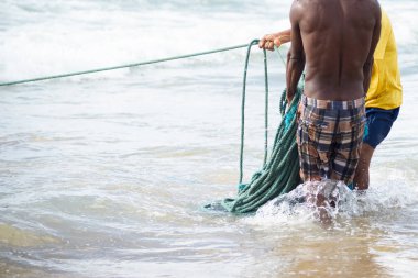 Kimliği belirsiz balıkçıların yarısı balık tuttuktan sonra balık ağı topluyor. Deniz ürünleri, hobi olarak balık tutmak. Brezilya
