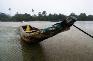 Kuru bir plajın kumlarına demirlenmiş bir balıkçı kanosu. Dalgalar çekildi. Şiddetli bulutlarla dolu yağmurlu bir gün. Taşıma araçları.