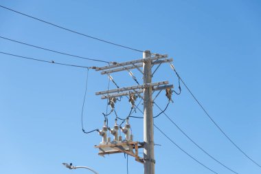 Mavi gökyüzüne karşı bir elektrik direği manzarası. Güç iletim ağı. Teknoloji.