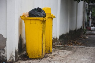 Siyah plastik çöp torbası olan sarı çöp kutusu.