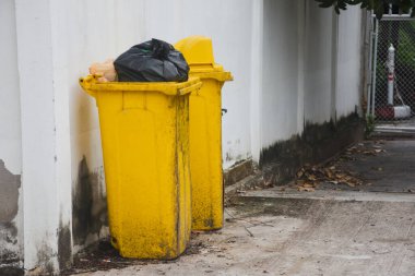 Siyah plastik çöp torbası olan sarı çöp kutusu.