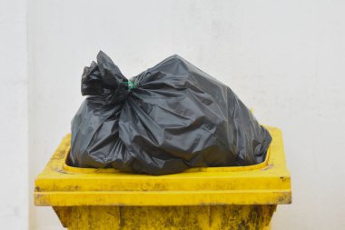 Siyah plastik çöp torbası olan sarı çöp kutusu.