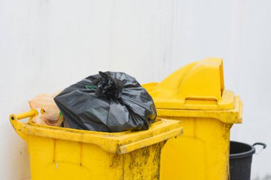 Siyah plastik çöp torbası olan sarı çöp kutusu.