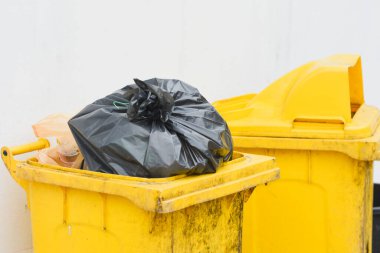 Siyah plastik çöp torbası olan sarı çöp kutusu.