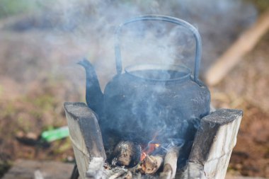Eski siyah bir çaydanlık kaynıyor ve yanıyor..