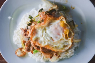 Fesleğenli domuz eti ve pirinçli kızarmış yumurta masada yemek için hazır..