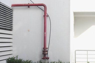 Beyaz beton zeminde kırmızı yangın musluğu