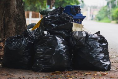 Siyah plastik çöp torbaları halka açık bir yolun kenarına konur..