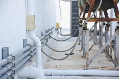 Beyaz bir duvara birkaç metal boru monte edilmiş..