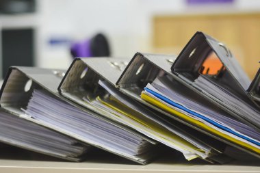 Belgeler ve kağıtlarla dolu birkaç klasörün yakın plan görüntüsü. Klasörler yatay olarak bir yüzeye yerleştirilmiş ve ucu kameraya dönük..