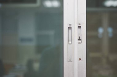 Metal çerçeveli sürgülü cam kapının yakın çekim görüntüsü. Odak noktası kapının kolları ve kilitlenme mekanizmaları.. 