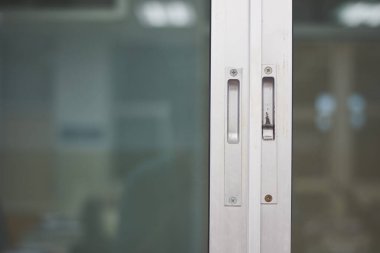 Metal çerçeveli sürgülü cam kapının yakın çekim görüntüsü. Odak noktası kapının kolları ve kilitlenme mekanizmaları.. 