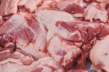 Metalik bir yüzeye yerleştirilmiş birkaç parça çiğ domuz eti. Et taze görünüyor, yağ ve kas dokusundan oluşan görünür bir mermer. Parçalar şekil ve boyut olarak değişir..