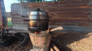 Geleneksel açık hava yemekleri. İçinde odun parçalarıyla doldurulmuş ateş olan metal bir soba var. Ocağın üstünde, saplı büyük metal bir tencere var..