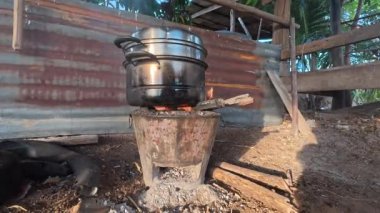 Geleneksel açık hava yemekleri. İçinde odun parçalarıyla doldurulmuş ateş olan metal bir soba var. Ocağın üstünde, saplı büyük metal bir tencere var..