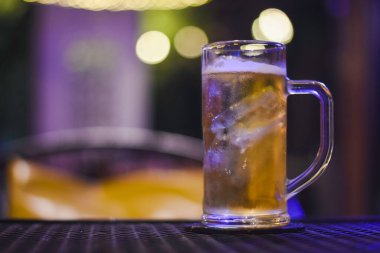 Açık renkli bir içecekle doldurulmuş berrak cam bardak, muhtemelen bira, tepesinde köpüklü bir kafa..