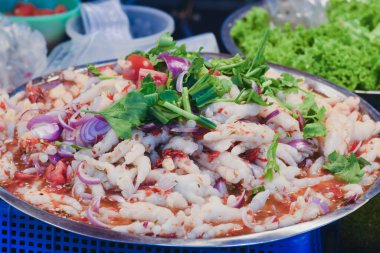 Tavuk ayağı, limon suyu, balık sosu ve kırmızı biber gibi malzemeleri içeren baharatlı ve keskin bir sosla karıştırılır.. 