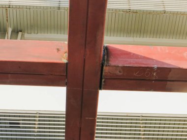 Binanın dış kısmı ön cephede zıt kırmızı çelikten bir çerçeve ile vurgulanırken, arka plan yatay kafes panelleri ve beyaz duvarları olan çok katlı bir binayı ortaya çıkarıyor..