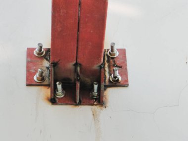 Taban plakası beton bir yüzeye sabitlenmiş, her iki tarafında da üç cıvata var. Çelik sütun kırmızıya boyanmış ve taban plakasına kaynaklanmış.. 