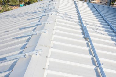 eğimli metal çatı. Çatıda bir dizi paralel çıkıntılar var ve muhtemelen güneş panelleri ya da başka bir tür ekipman kurulumu için sayısız montaj parantezi ile donatılmıştır.