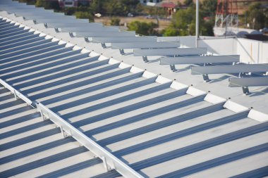 eğimli metal çatı. Çatıda bir dizi paralel çıkıntılar var ve muhtemelen güneş panelleri ya da başka bir tür ekipman kurulumu için sayısız montaj parantezi ile donatılmıştır.