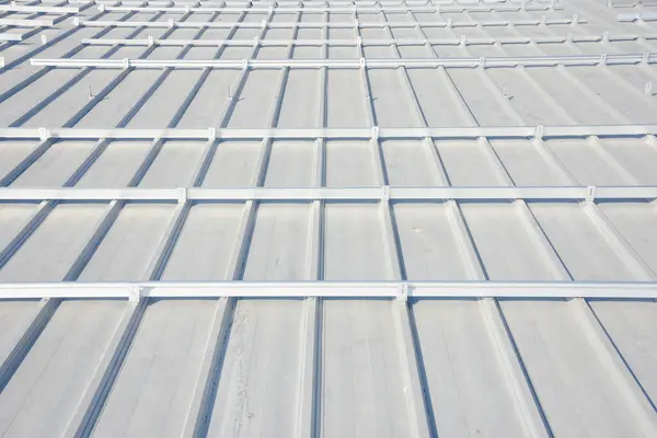 eğimli metal çatı. Çatıda bir dizi paralel çıkıntılar var ve muhtemelen güneş panelleri ya da başka bir tür ekipman kurulumu için sayısız montaj parantezi ile donatılmıştır.