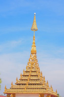 Güzel süslenmiş altın kule, muhtemelen bir tapınağın parçası ya da belirgin bir dini yapı, açık mavi gökyüzüne karşı kurulmuş..