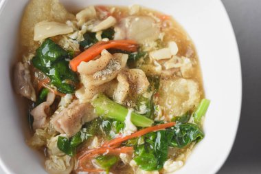 Domuz eti ve lahana ile karıştırılmış erişte, üstünde domuz eti ile servis edilir. Çin-Tayland yemeği, adı 