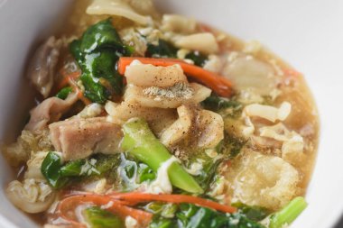 Domuz eti ve lahana ile karıştırılmış erişte, üstünde domuz eti ile servis edilir. Çin-Tayland yemeği, adı 