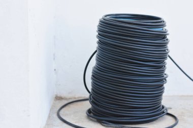 Büyük siyah kablo ya da kablo sarmalı, düzgün bir şekilde yaralanmış ve yere yerleştirilmiş. Kablo esnek bir maddeden yapılmış gibi görünüyor, muhtemelen kauçuk ya da plastik..