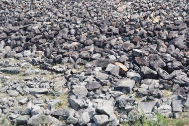 Değişen şekil ve boyutlarda taşların ve kayaların çeşitliliği. Ağırlıklı olarak koyu gri, siyah ve kahverengi tonlarında kayalar bir araya toplanarak sert ve düzensiz bir doku oluştururlar..