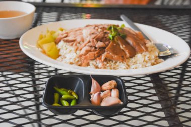 Taze yeşil biber ve küçük siyah servis kaselerinde dizilmiş büyük sarımsak karanfilleri. Servis kaseleri siyah metal bir şebeke masasına yerleştiriliyor, rahat bir his veriyor..