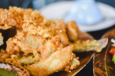 Kızarmış yiyeceğe yakın çekim. Kızarmış balık ya da hamurla kaplanmış deniz ürünleri. Kahverengi ve çıtır çıtır olana kadar kızartılmış. Koyu ahşap bir tabakta yemek..