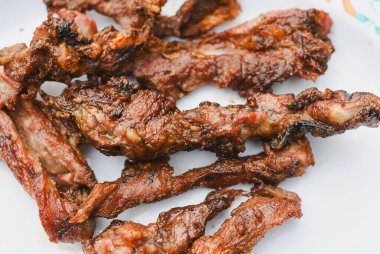 Tabakta servis edilen birkaç parça pişmiş, ızgara ya da kızarmış etin yakın çekim görüntüsü.