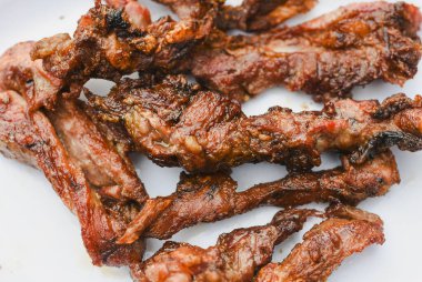 Tabakta servis edilen birkaç parça pişmiş, ızgara ya da kızarmış etin yakın çekim görüntüsü.