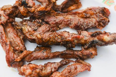 Tabakta servis edilen birkaç parça pişmiş, ızgara ya da kızarmış etin yakın çekim görüntüsü.