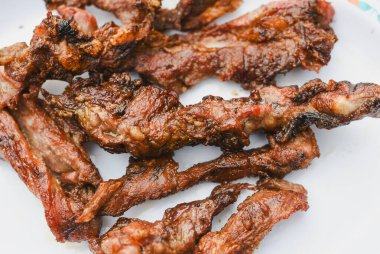 Tabakta servis edilen birkaç parça pişmiş, ızgara ya da kızarmış etin yakın çekim görüntüsü.