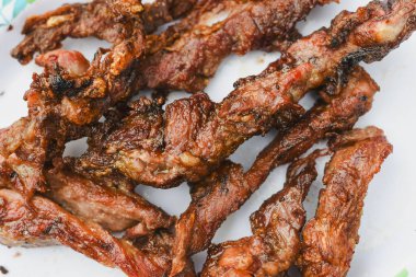 Tabakta servis edilen birkaç parça pişmiş, ızgara ya da kızarmış etin yakın çekim görüntüsü.