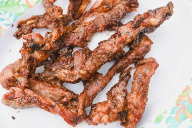 Tabakta servis edilen birkaç parça pişmiş, ızgara ya da kızarmış etin yakın çekim görüntüsü.