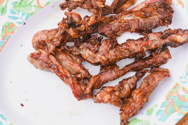 Tabakta servis edilen birkaç parça pişmiş, ızgara ya da kızarmış etin yakın çekim görüntüsü.