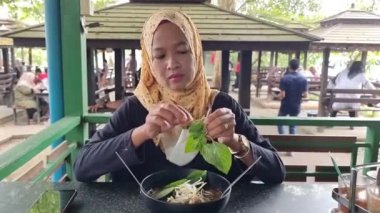 Asyalı Müslüman kadın erişte dükkanında erişte yemek zorunda.